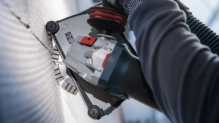 Person wearing safety equipment uses a wall chaser to cut a straight line into concrete.